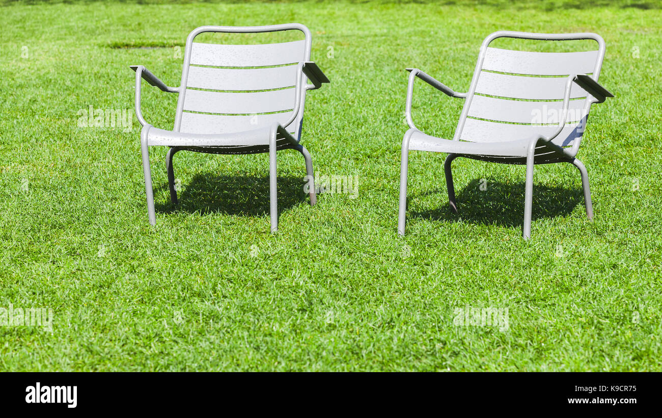 2 Outdoor metall Stühle stehen auf frische grüne Gras im Sommer Park Stockfoto
