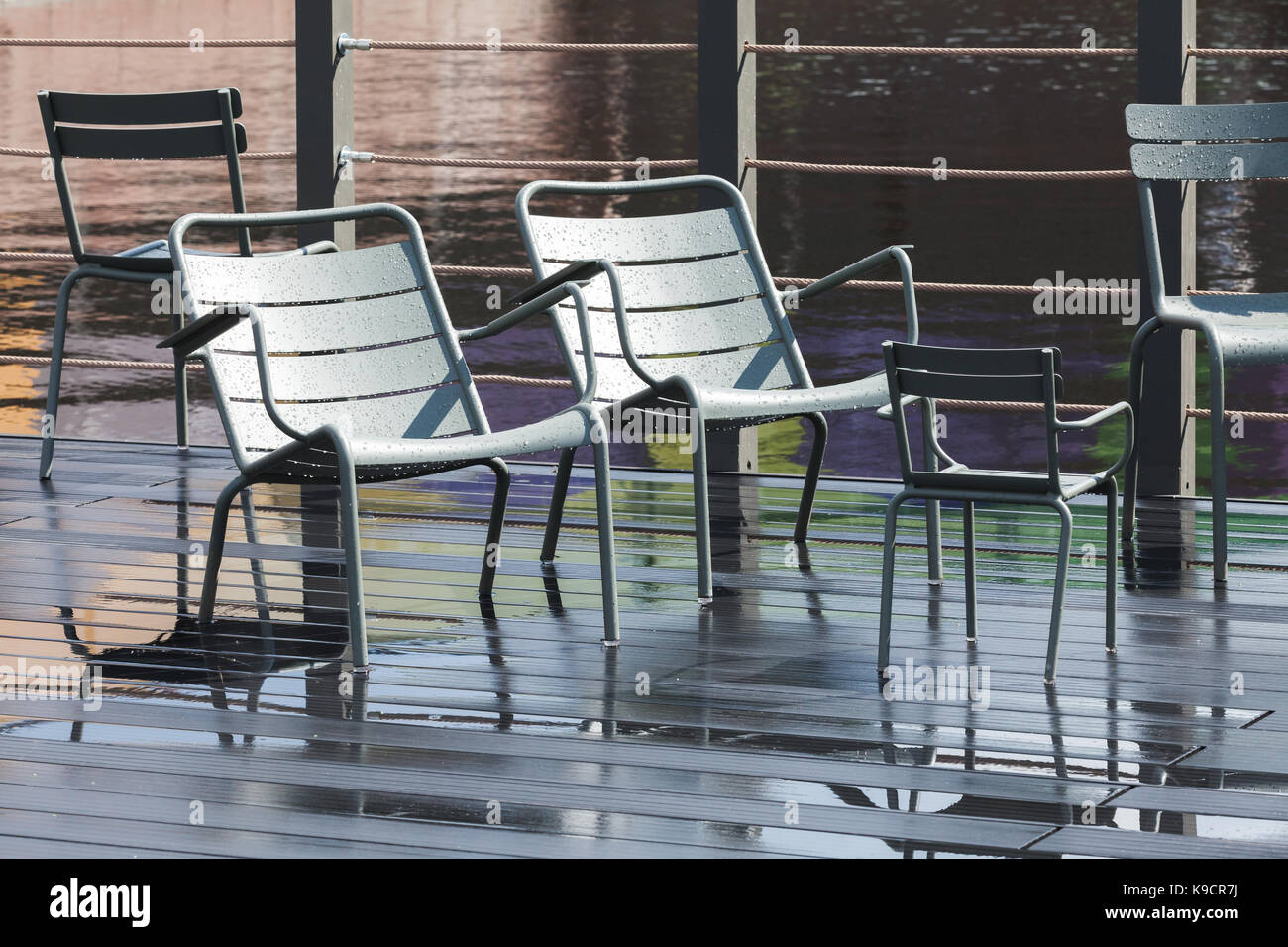 Leere outdoor grau Metall Stühle stehen auf nassen Pier Stockfoto