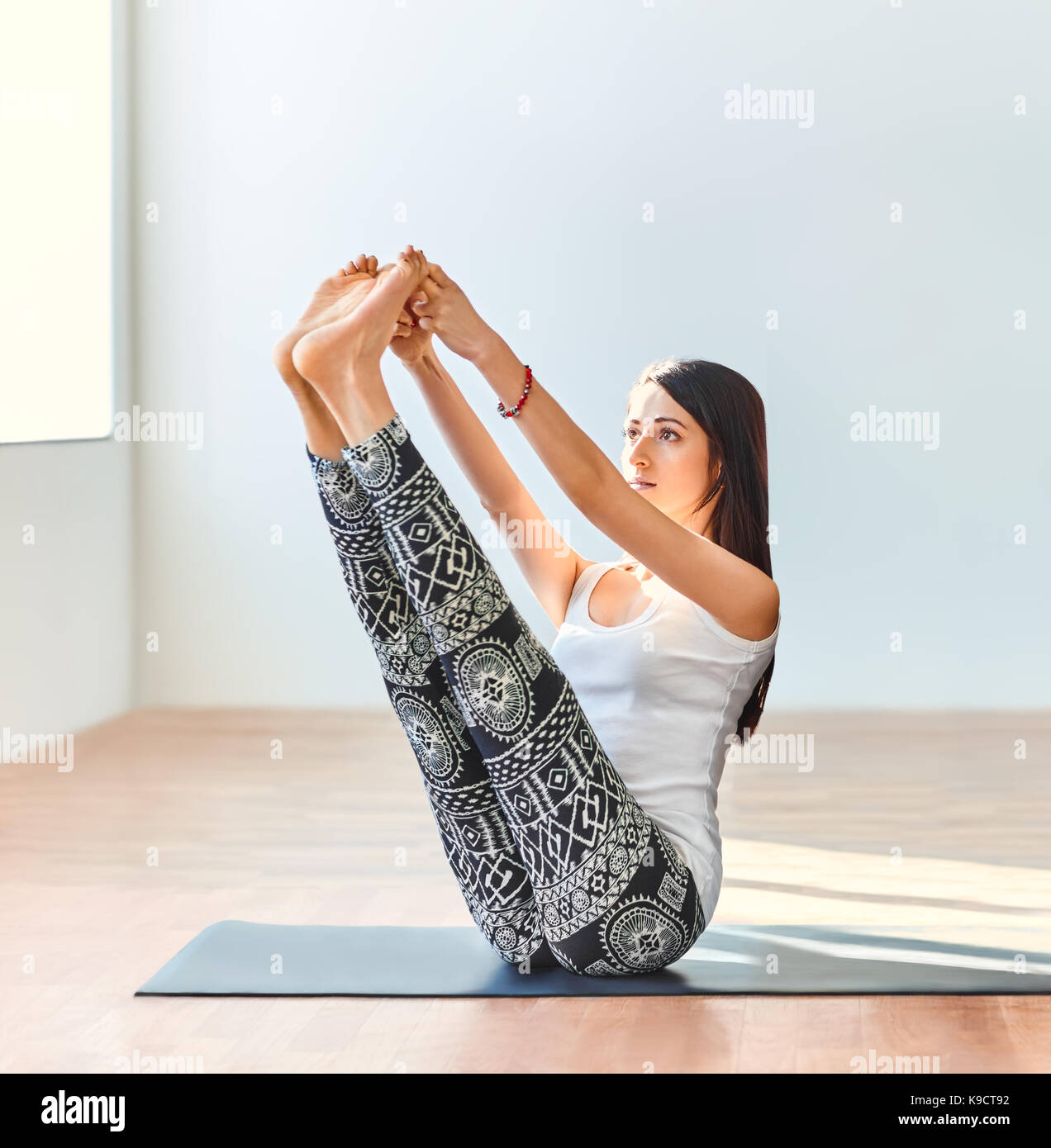 Junge Frau Yoga Asana sowohl die großen Zehen darstellen. Ubhaya Padangusthasana Stockfoto