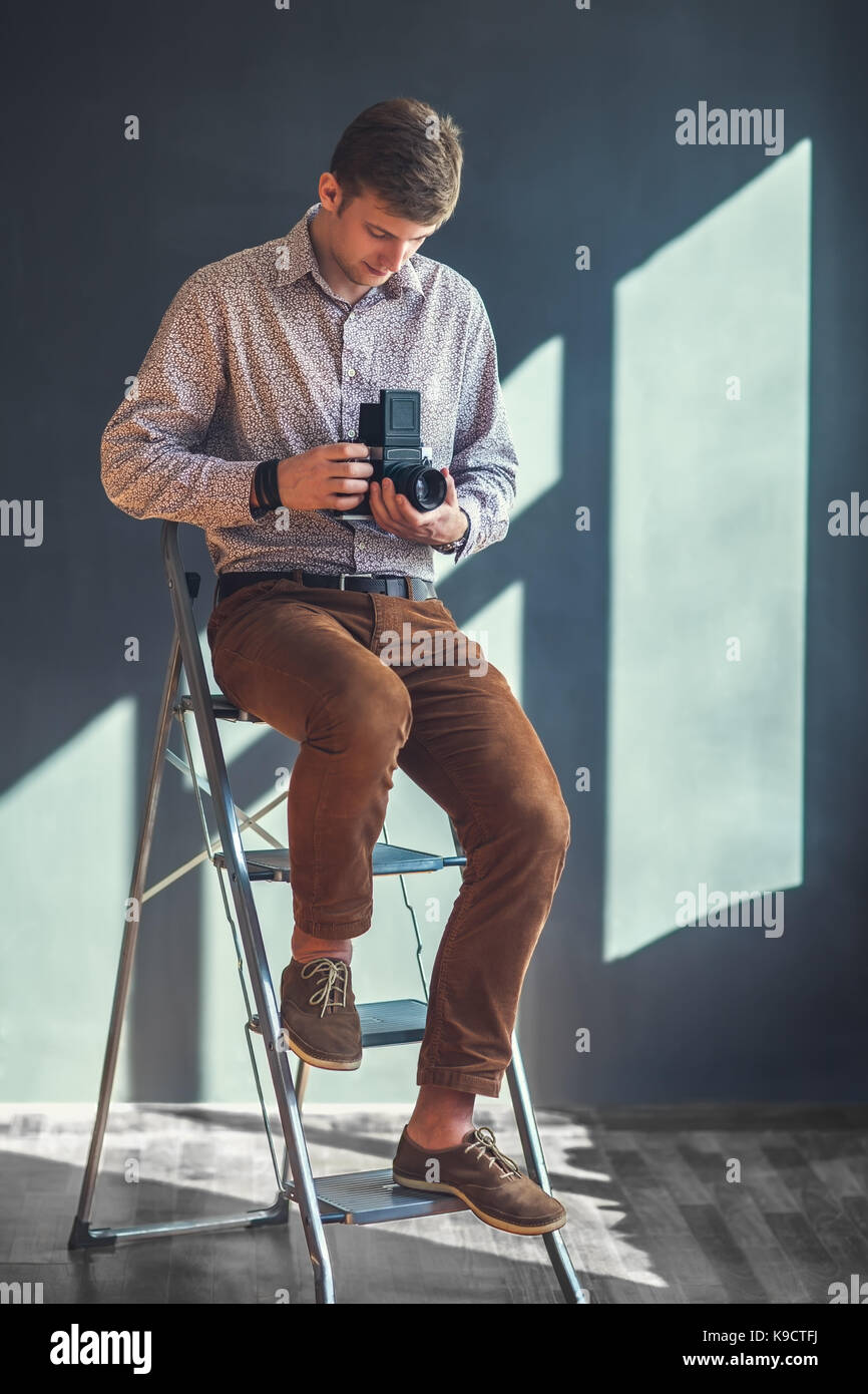 Portrait von stattlicher Mann mit retro Mitte Kamera im Studio. Fotograf Stockfoto