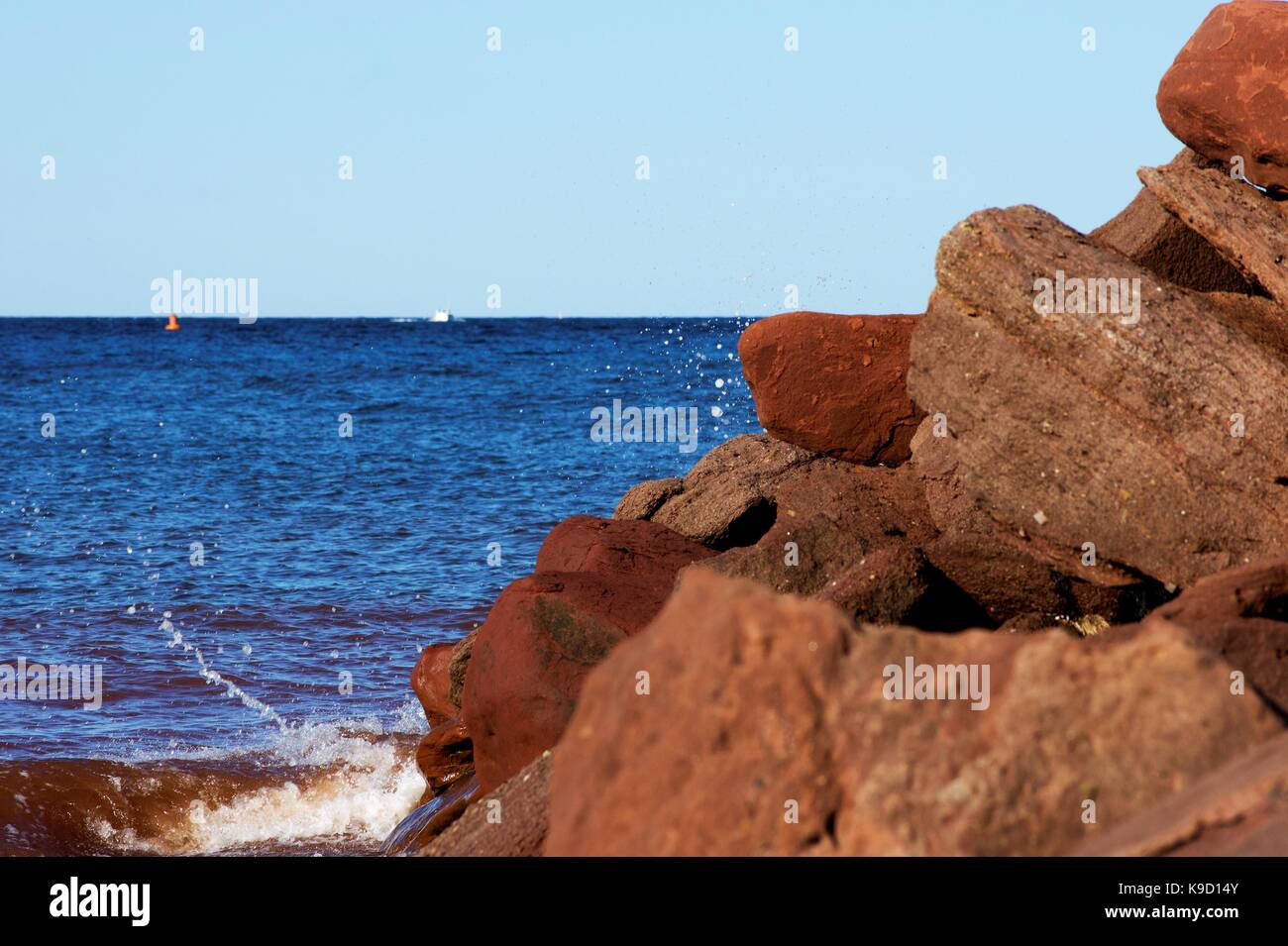 Welle Brechen von Gestein mit Boot und Boje im Hintergrund Stockfoto