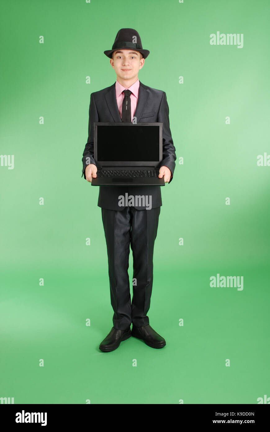 Volle Länge Portrait von zuversichtlich reife Geschäftsmann mit einem Laptop in formals stehend über grünen Hintergrund isoliert Stockfoto