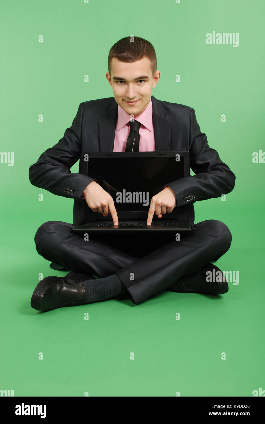 Volle Länge Portrait von zuversichtlich reife Geschäftsmann, die in Laptops in formals Sitzen über grüne Hintergrund isoliert arbeiten Stockfoto