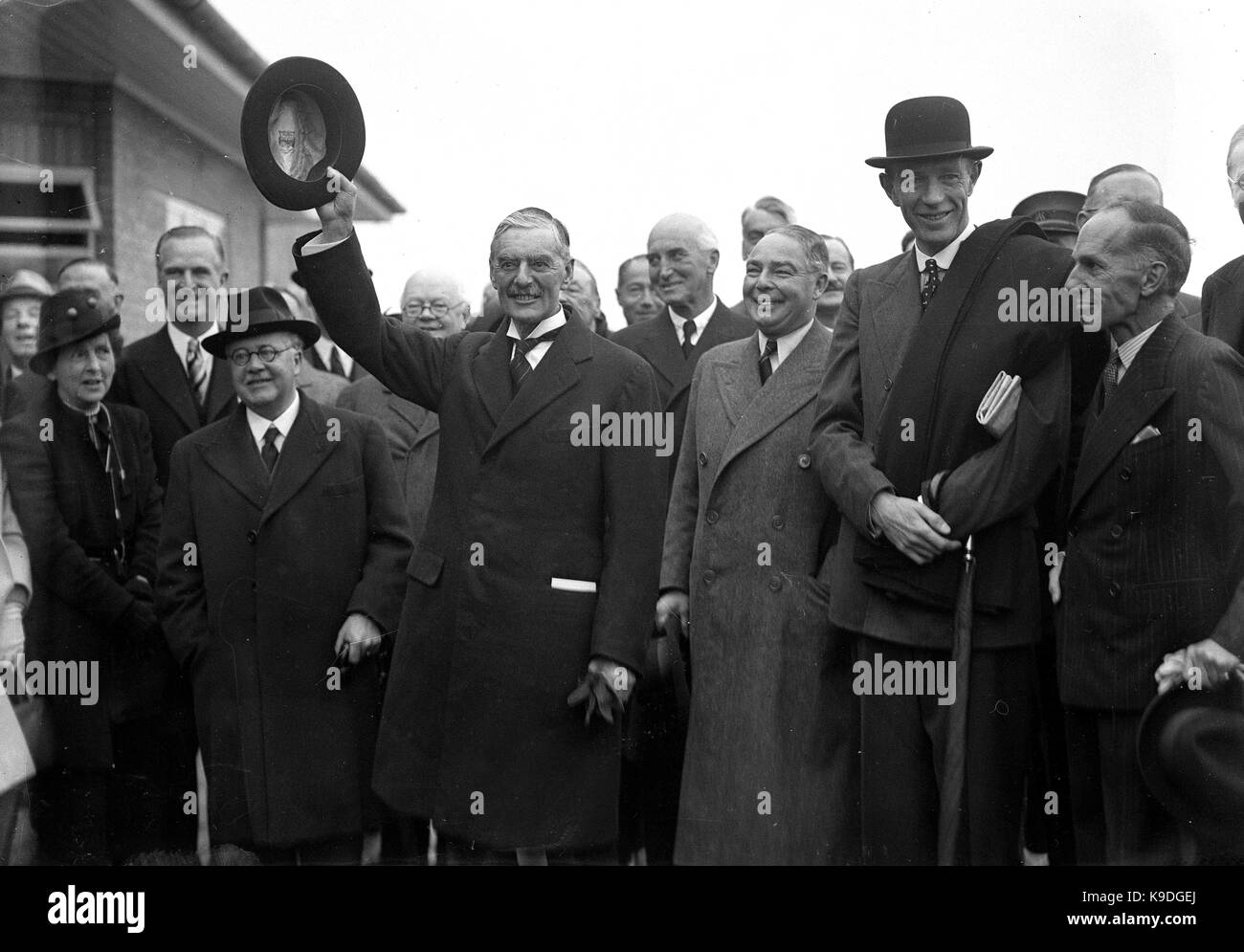 Der britische Premierminister Neville Chamberlain verlassen für seinen Gipfel mit dem Reichskanzler Adolf Hitler in München. Premierminister Chamberlain mit dem Papier unterzeichnet von Hitler und klemmt sich selbst aus seiner Tasche nach der Erklärung zu der wartenden Menge "Frieden in unserer Zeit" 3. Oktober 1938. Mit ihm sind Sir Kingsley Holz, Leslie Hore-Belisha, Lord Halifax. Stockfoto