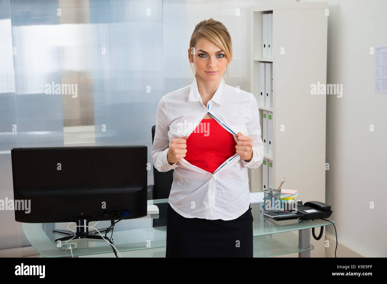 Porträt der jungen Geschäftsfrau reißt ihr Shirt offenbart ein Superheld Anzug Stockfoto