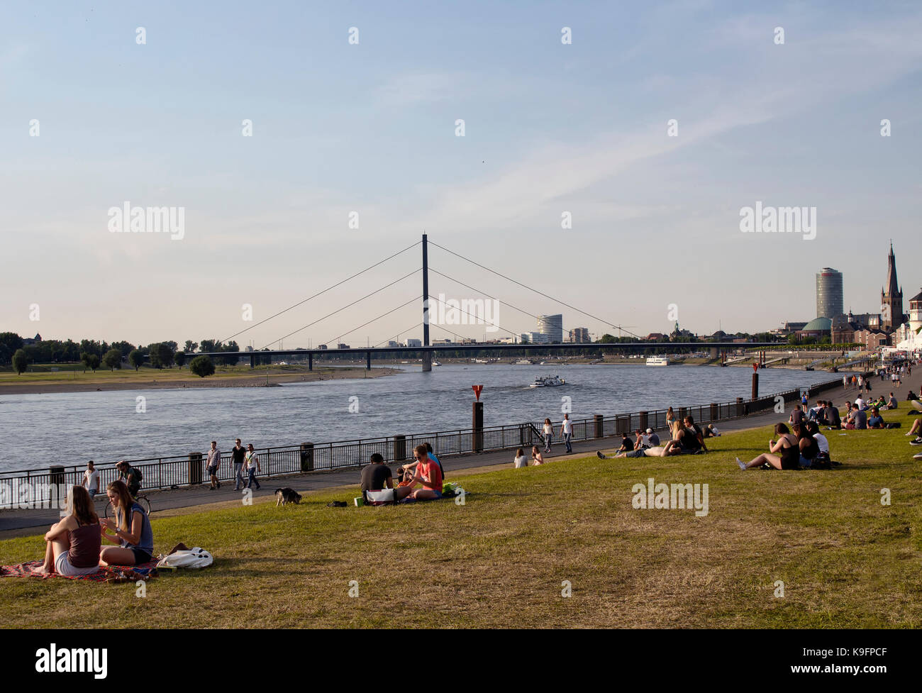 Die Menschen genießen Sie sonnige Wetter und hängen von Rhein (Rhein) Fluss in Dusselforf. Brucke Oberkassler Brücke ist im Hintergrund. Stockfoto