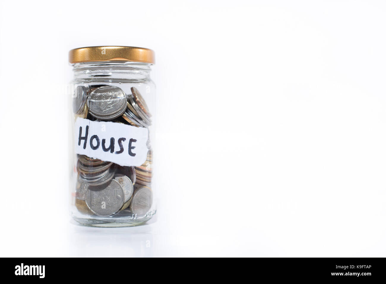 Münzen in ein Glas mit einer Note geschrieben 'Haus'. Auf einem weißen Hintergrund. Geld sparen Haus kaufen. kostenlose Kopie. Speichern Konzept. Malaysia cur Stockfoto