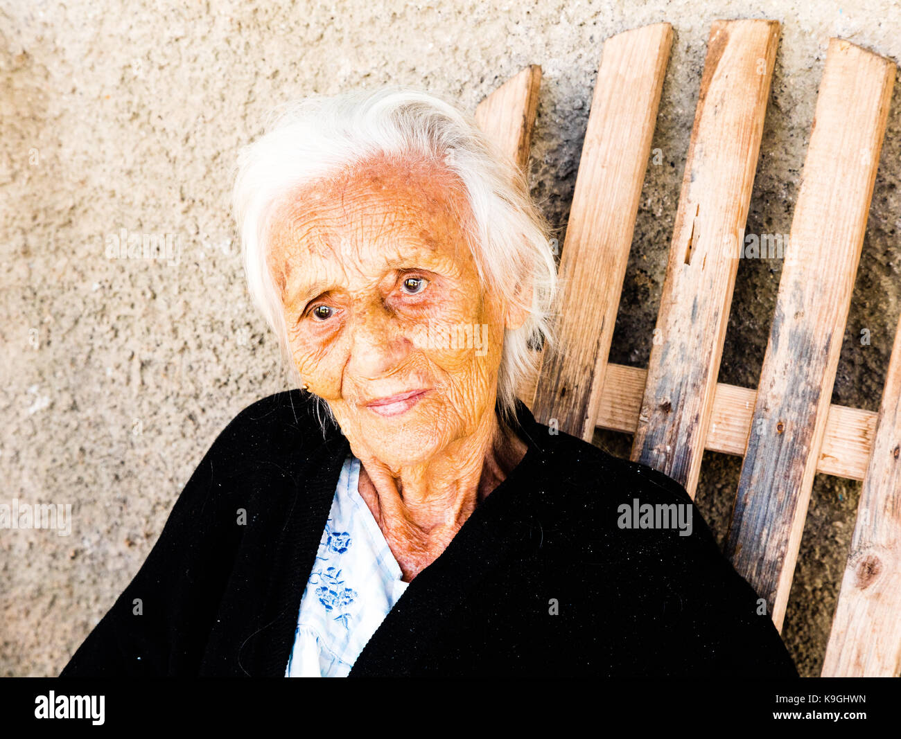 Lächelnd weiß behaarten alte Dame sitzen auf einem hölzernen Schaukelstuhl außerhalb ihrer Heimat, Vinales, Kuba Stockfoto