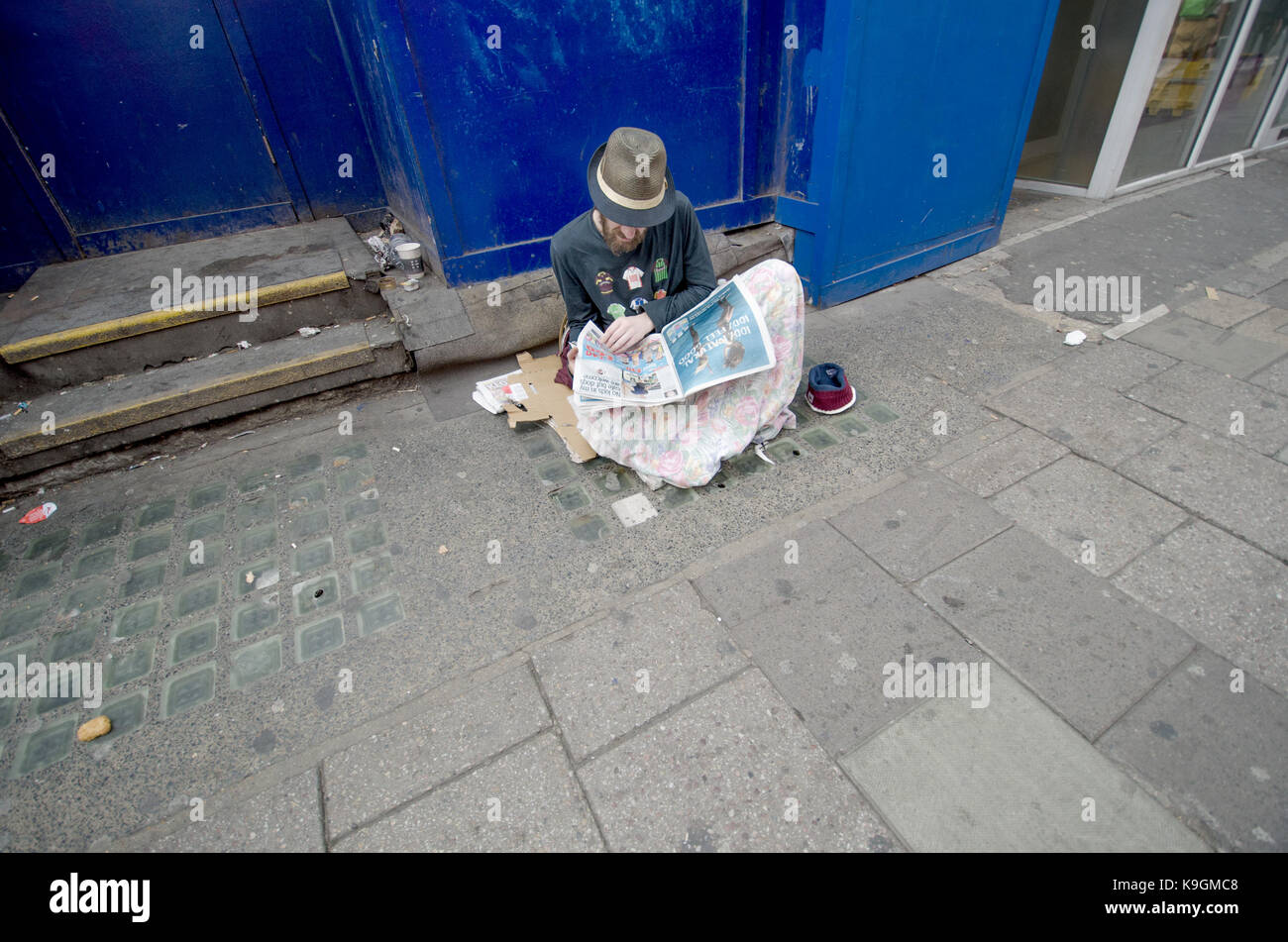 London, England, UK. Obdachlosen eine Zeitung lesen Stockfoto