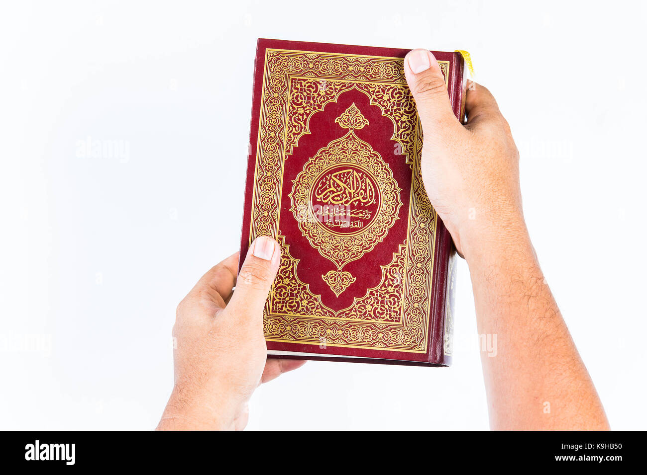 Koran in der Hand, Koran in der Hand - das heilige Buch der Muslime, auf weißem Hintergrund Stockfoto