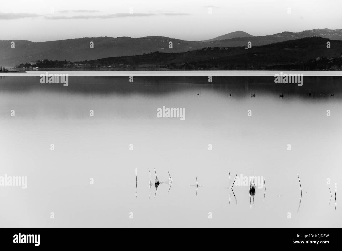 Ein See in der Abenddämmerung, mit weichem Licht, die fernen Hügel und Berge, Fischernetze im Vordergrund eine viel leerer Raum Stockfoto