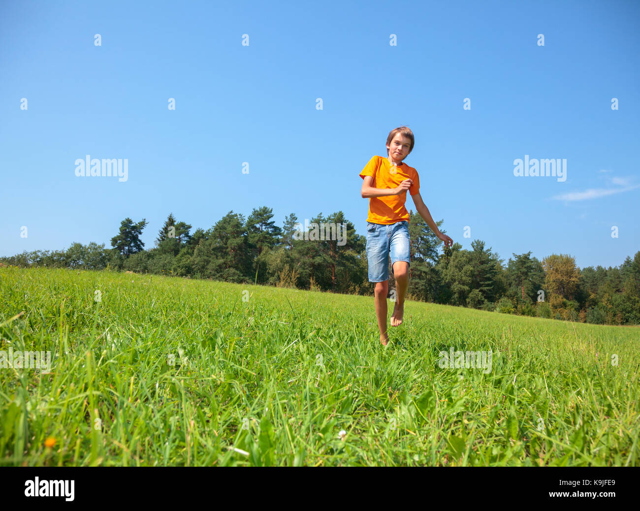 Junge genießen Sommer laufen durch eine sonnige Wiese in einem Sommer Wald Stockfoto