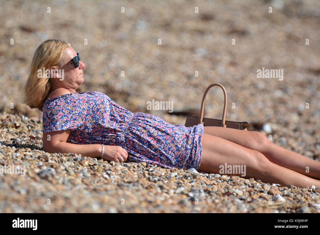 Eine Frau in einem Kleid mit am Strand relaxen in der Sonne in Großbritannien. Stockfoto