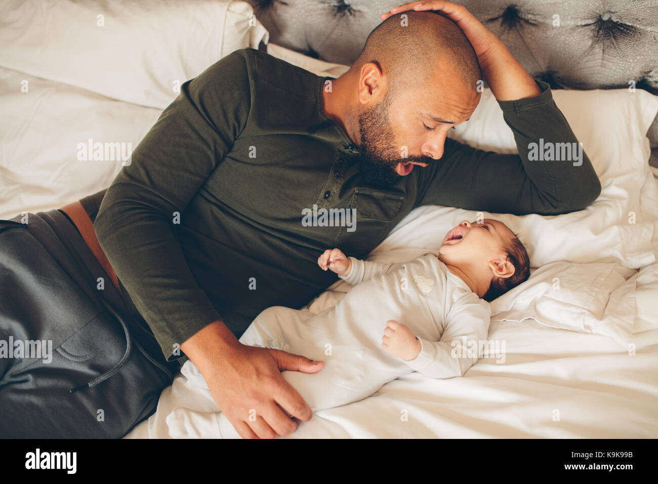 Gerne Vater mit seinem Sohn spielen zu Hause auf dem Bett. Mann und kleinen Baby im Schlafzimmer. Stockfoto