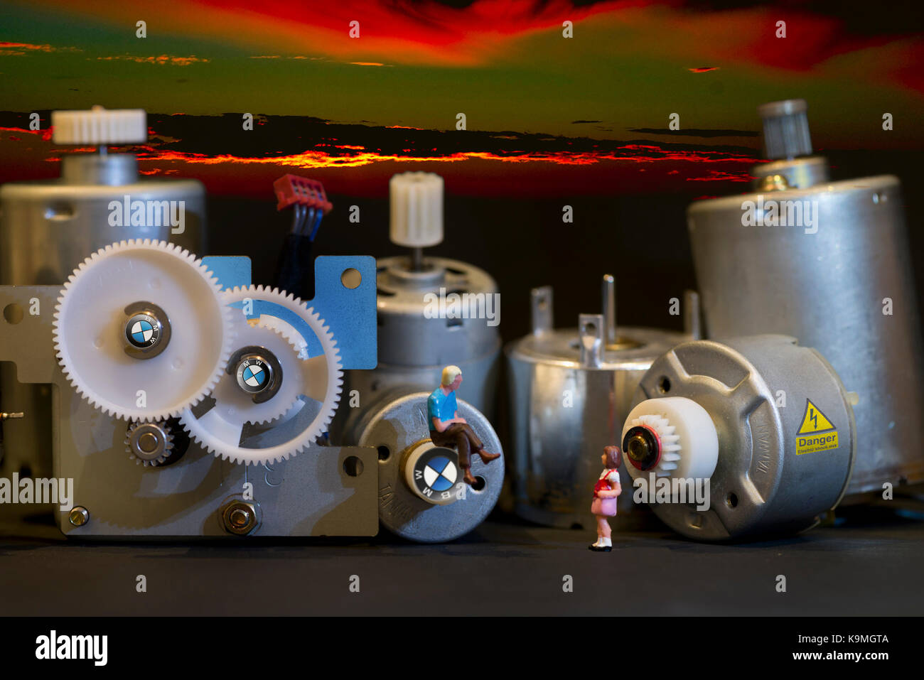 Eines Tages alle Autos elektrisch sein" - winzige Mann sitzt auf Zahnrad der großen Elektromotoren spricht mit seiner Tochter über die Zukunft der Elektroautos Stockfoto