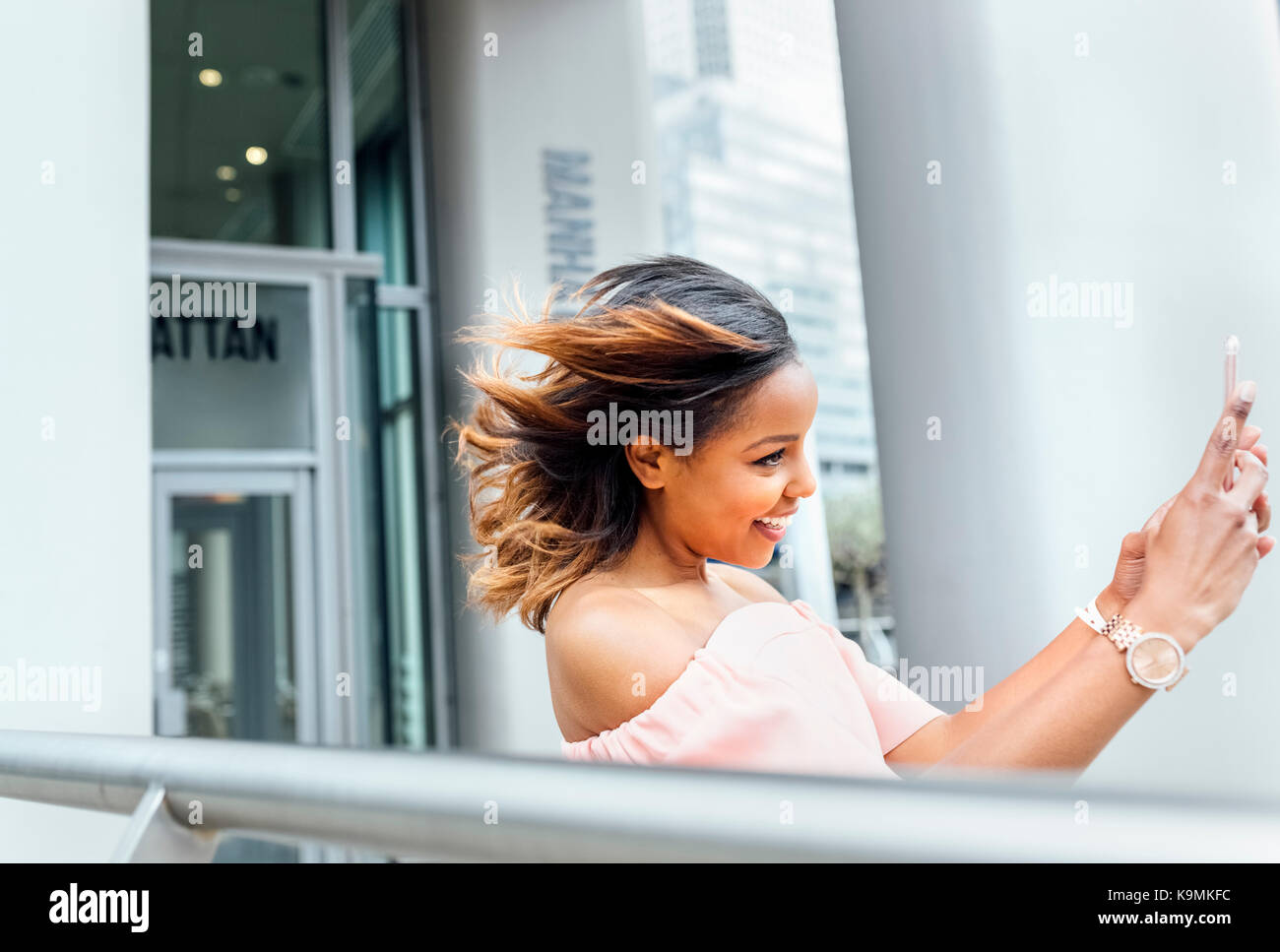 Lächelnde Frau mit einem selfie in der Stadt Stockfoto