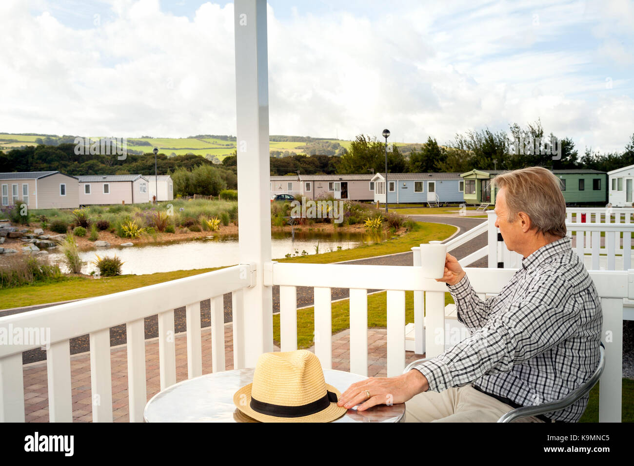 Ältere Menschen Trinken einer Tasse Kaffee sitzen auf der Veranda eines Luxus-mobilheim im Norden von Wales, die in der malerischen Aussicht auf die walisische Land Stockfoto