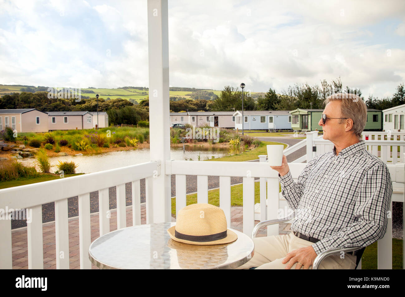 Ältere Menschen Trinken einer Tasse Kaffee sitzen auf der Veranda eines Luxus-mobilheim im Norden von Wales, die in der malerischen Aussicht auf die walisische Land Stockfoto