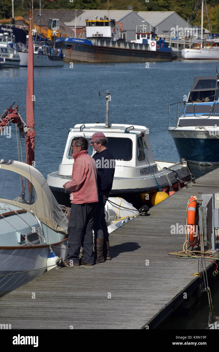 Zwei Männer mittleren Alters, stehend auf einem Steg oder hafenmauer Kai neben ihre Yachten über Segeln und ein gemeinsames Interesse an der Yachting. Hobbys Stockfoto