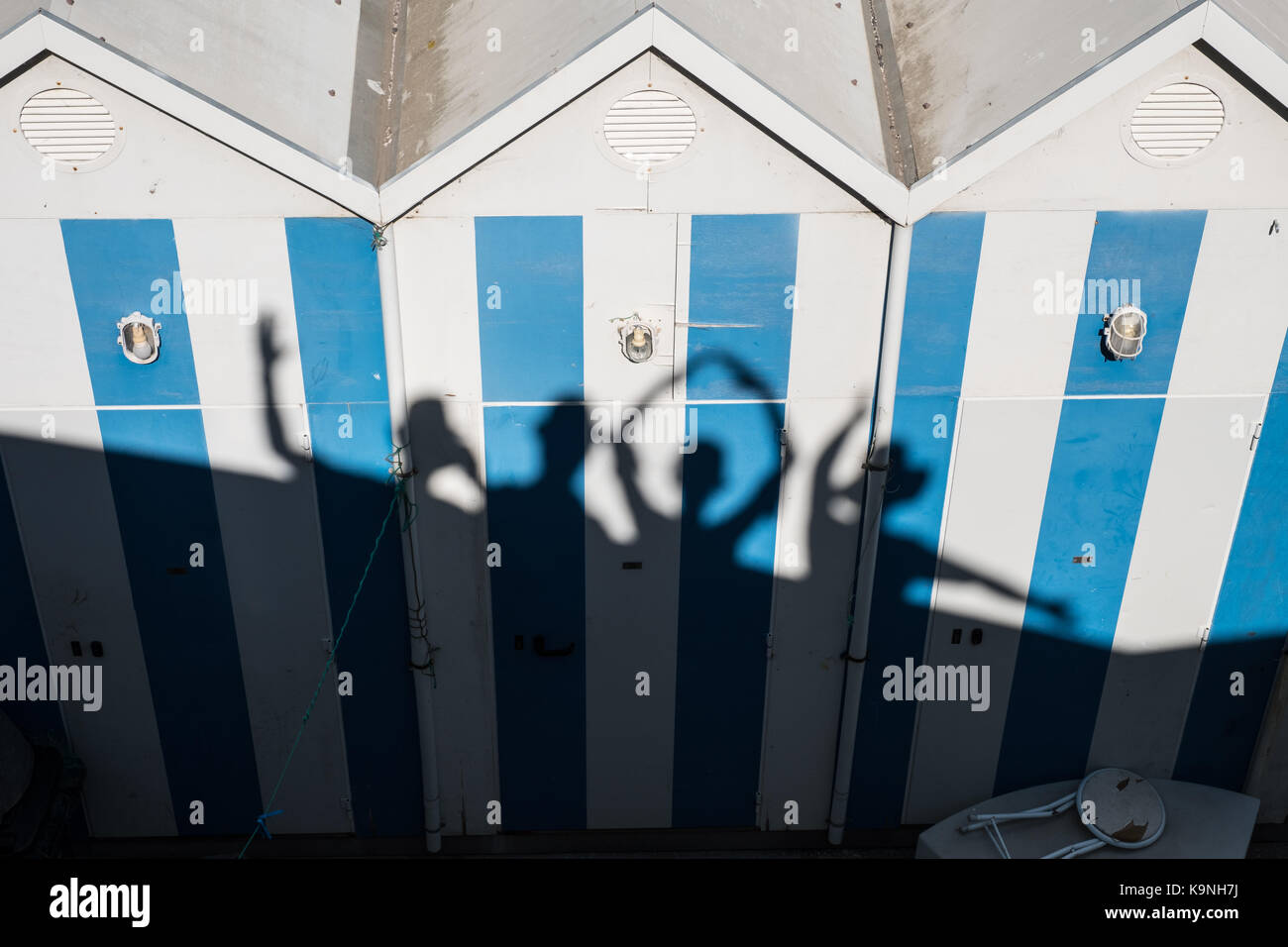 Silhouette von vier Personen gegen einen blau-weiß gestreiften Strandhütte Stockfoto