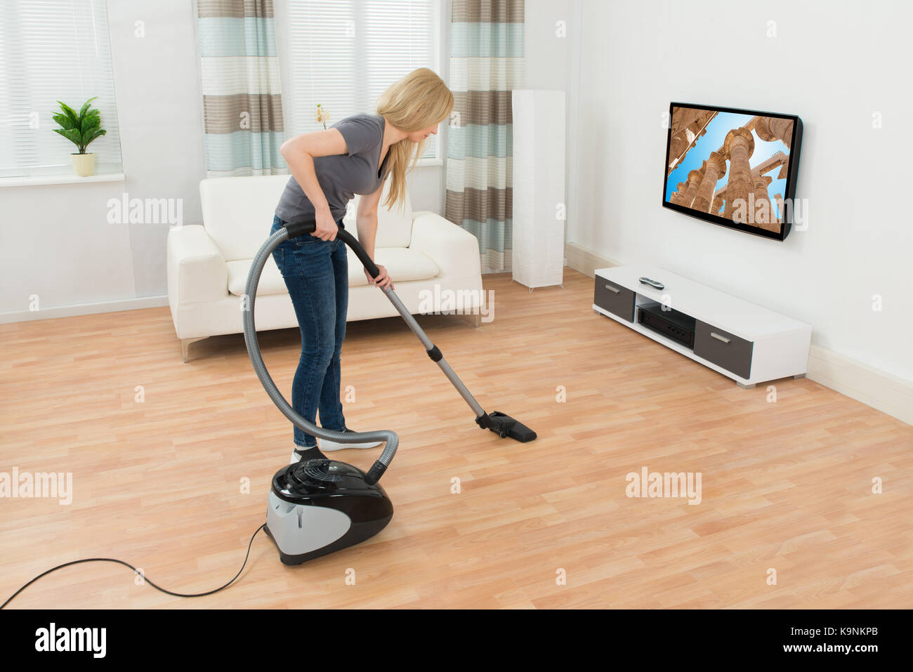 Junge Frau Reinigung Boden mit Staubsauger zu Hause Stockfoto