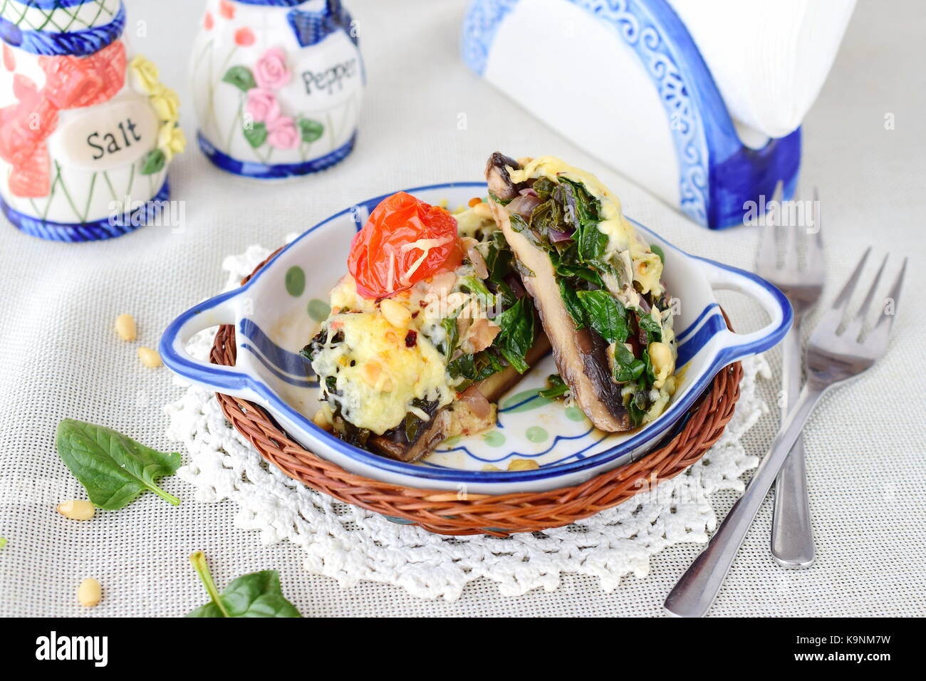 Gegrillte Portobello Pilze mit Spinat, Pinienkerne, Zwiebeln und Käse in einem keramischen Topf. Gesunde Ernährung Konzept. Mediterrane Lebensart Stockfoto