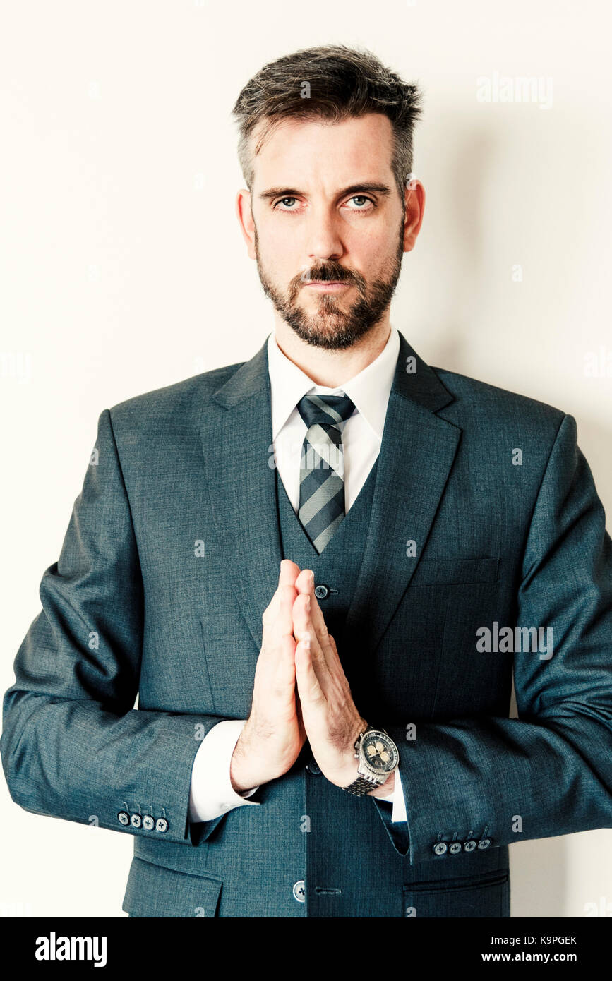 Gut aussehender Geschäftsmann in Anzug und Krawatte, Zen yoga Pose mit Hände zusammen. Stockfoto