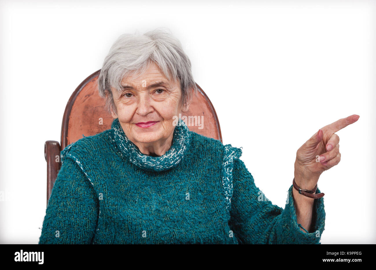 Alte Frau poiting Ihren linken Finger auf etwas und Blick in die Kamera, vor einem weißen Hintergrund isoliert. Stockfoto