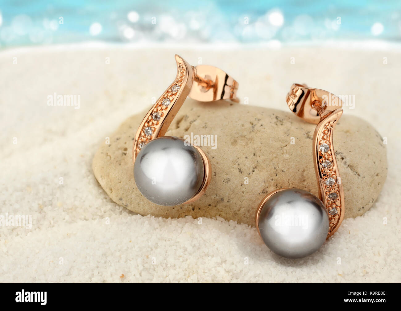 Schmuck Ohrringe mit schwarzen Perlen auf Sand strand Hintergrund Kopie Raum Stockfoto