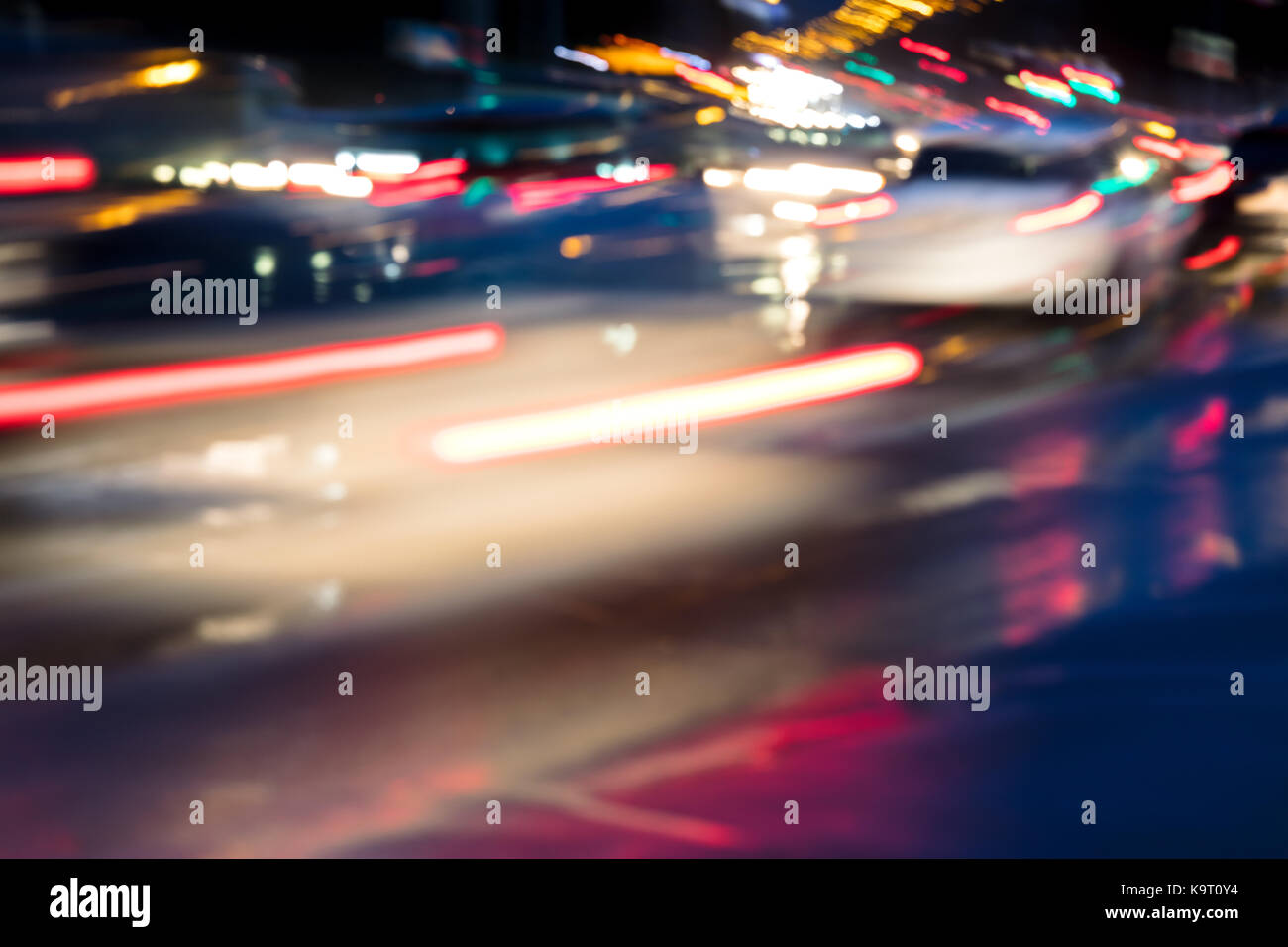Verschwommene Sicht auf city night lights und Autos in Bewegung. Verkehr in einer regnerischen Nacht. Stockfoto