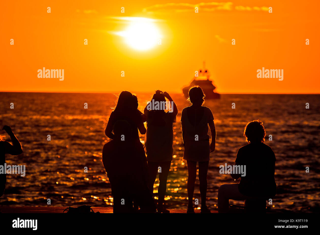 Menschen Silhouetten an den goldenen Sonnenuntergang am Meer und Yachtcharter auf Horizont, Zadar, Kroatien Stockfoto