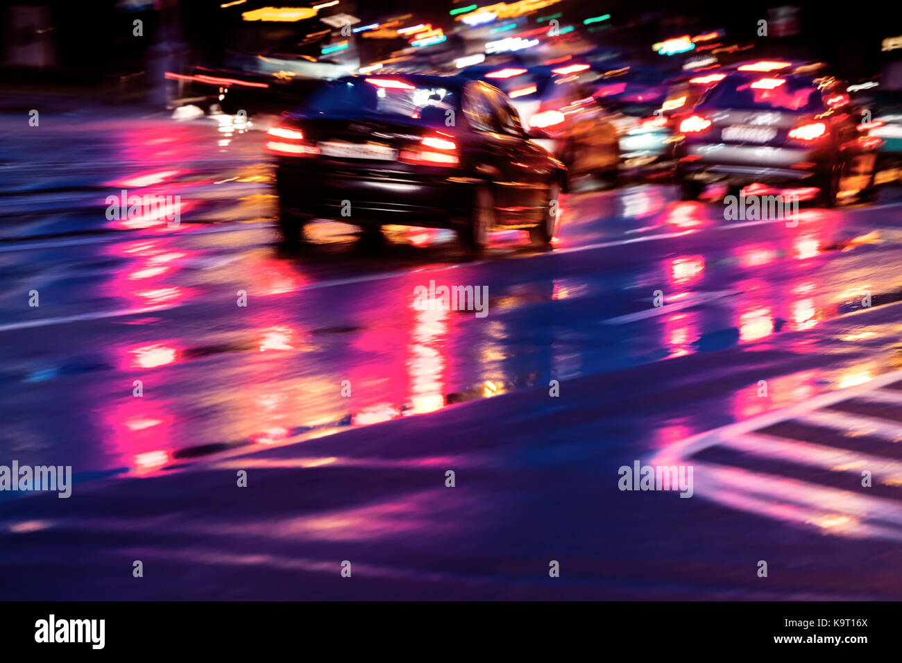 Verschwommen Stadtverkehr mit bunten hellen Scheinwerfer. Autos auf Nacht Straße nach Regen zu fahren. Stockfoto