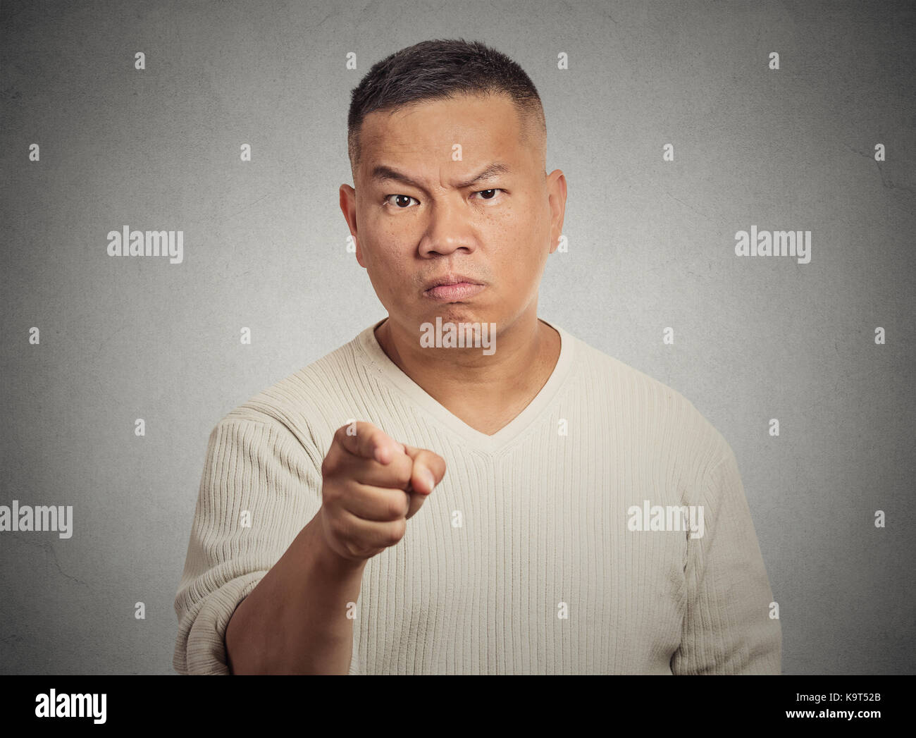 Zorniger Mann, der seine Finger auf jemand auf grauen Hintergrund isoliert Stockfoto