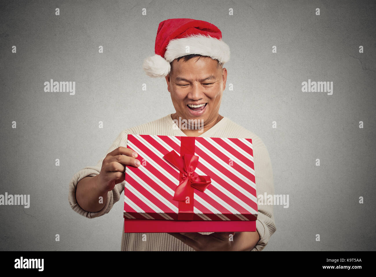 Closeup Portrait Glücklich, aufgeregt überrascht im mittleren Alter Mann öffnen Auspacken roter Geschenkbox isoliert grauen Hintergrund, seine Gegenwart. Positive Stockfoto