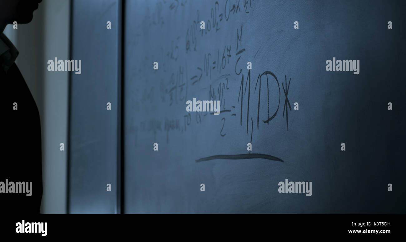 Wissenschaftler stehen in der Nähe von Formeln auf der Schiefertafel. Physik Formeln auf der schwarzen Tafel Stockfoto