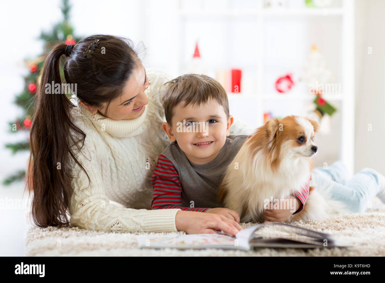 Glückliche Familie und der Hund Ausgaben zusammen Weihnachten zu Hause in der Nähe der Weihnachtsbaum. Neues Jahr Konzept Stockfoto