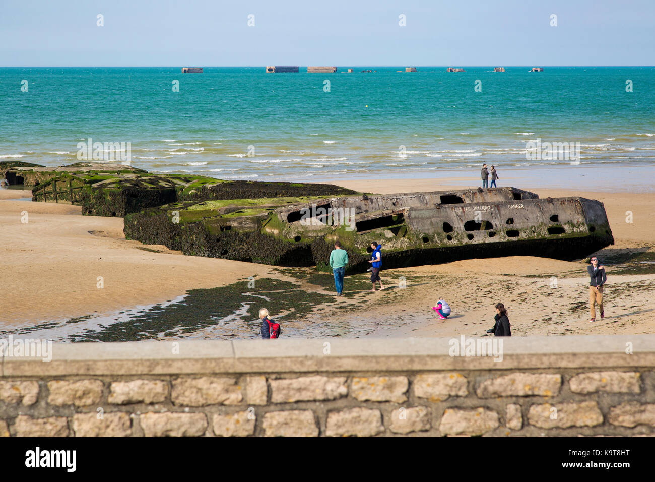 Touristen anzeigen Mulberry Hafen caissons (temp D-Tag Hafen) am Strand von Arromanches-les-Bains, Calvados, Normandie, Frankreich Stockfoto