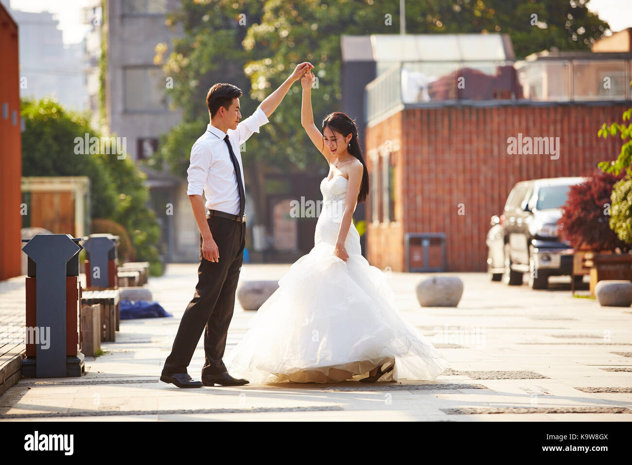 Junge asiatische Braut und Bräutigam in Wedding Dress tanzen auf dem Parkplatz. Stockfoto