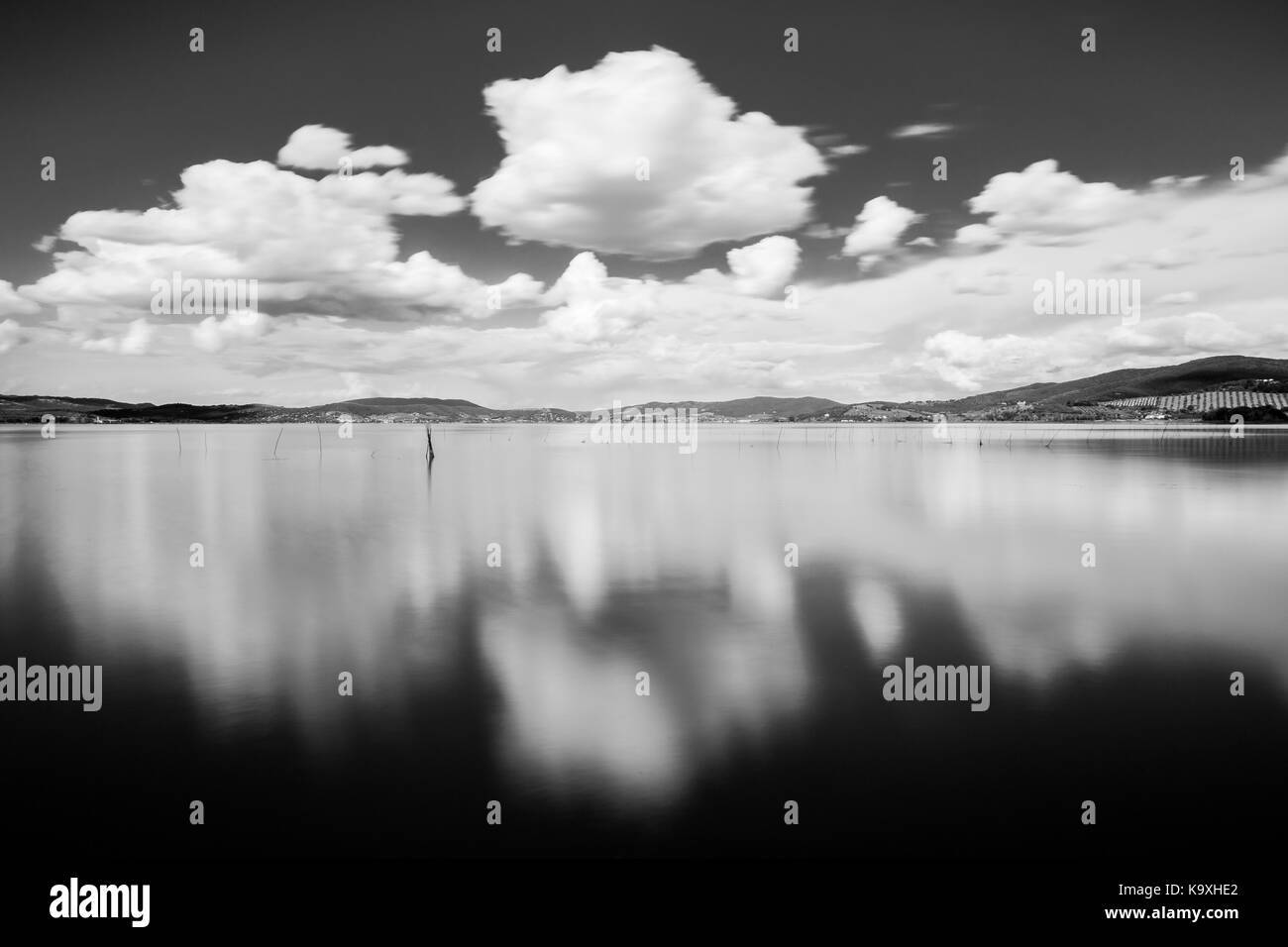 Langzeitbelichtung, Blick auf den See, mit beweglichen weißen Wolken perfekt auf dem Wasser widerspiegeln Stockfoto