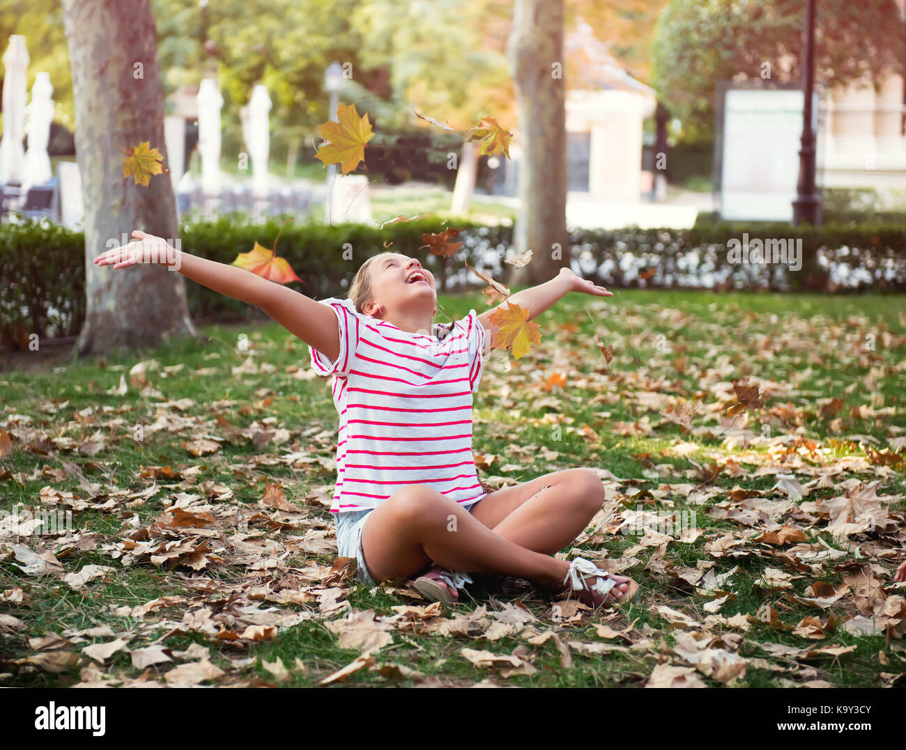 Herbst lifestyle foto kind wirft die Blätter und Spaß haben, positive kleines Mädchen Stockfoto