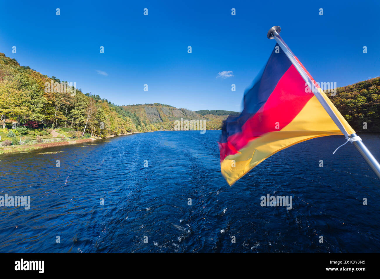 Deutsche Flagge auf einem Schiff auf dem Rursee in der Eifel in Deutschland im Herbst. Stockfoto