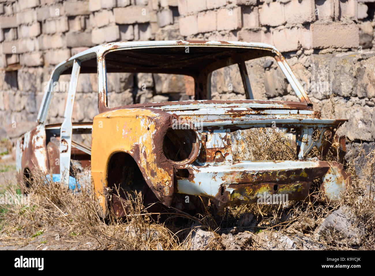 Aufgegeben und rostige Skelett eines sowjetischen russischen Auto wachsenden Heu innen an der Seite des Gebäudes in Ararat Provinz am 4. April 2017. Stockfoto