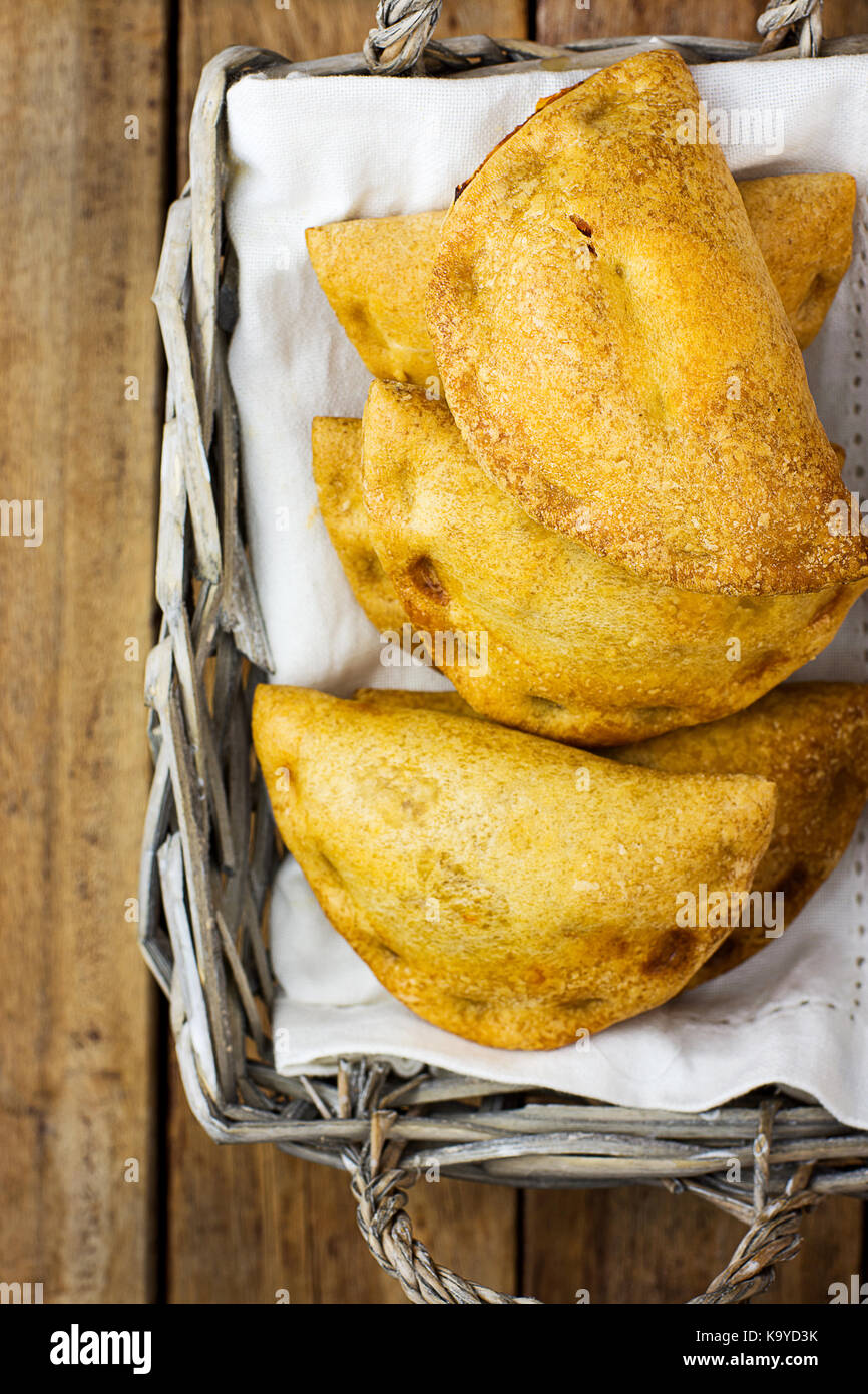 Frisch gebackene empanadas Umsatz Torten mit Gemüse Käse in Tomatensauce im Weidenkorb. Plank Holz Hintergrund. Spanisch Lateinamerika tr Stockfoto