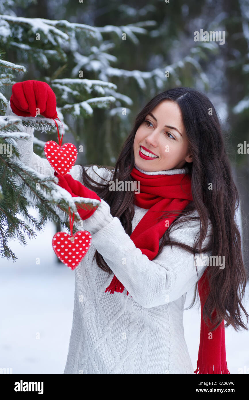 Weihnachten, Winter Urlaub, Valentinstag und Personen Konzept - glückliche junge Frau schmücken Weihnachtsbaum. Winter Outdoor Portrait von Mädchen in Pullover, r Stockfoto