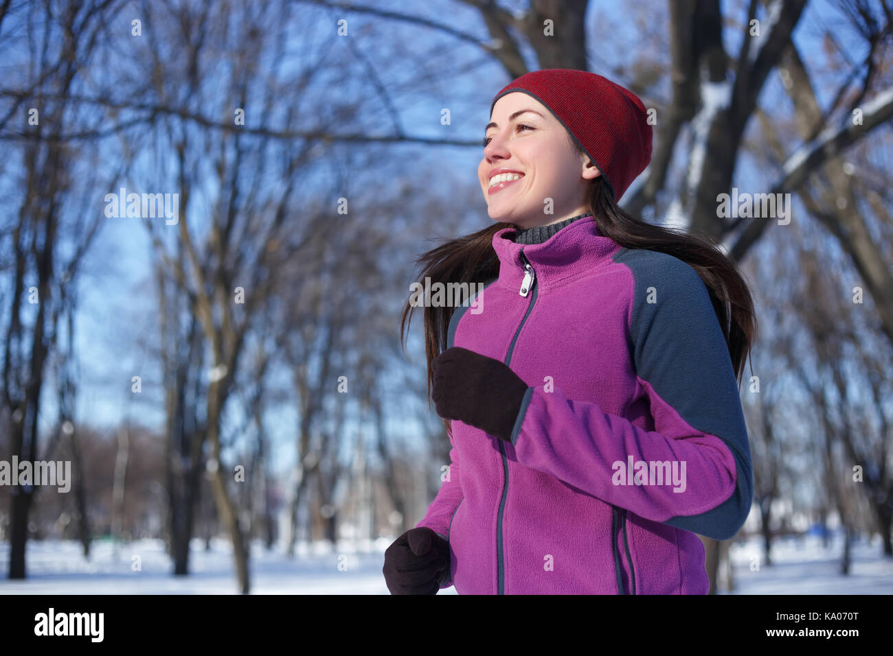 Laufsport Frau. Läuferin Joggen im kalten Winter Wald tragen warme Sportlich läuft Kleidung und Handschuhe. Fitness Happy girl läuft im Winter Stockfoto