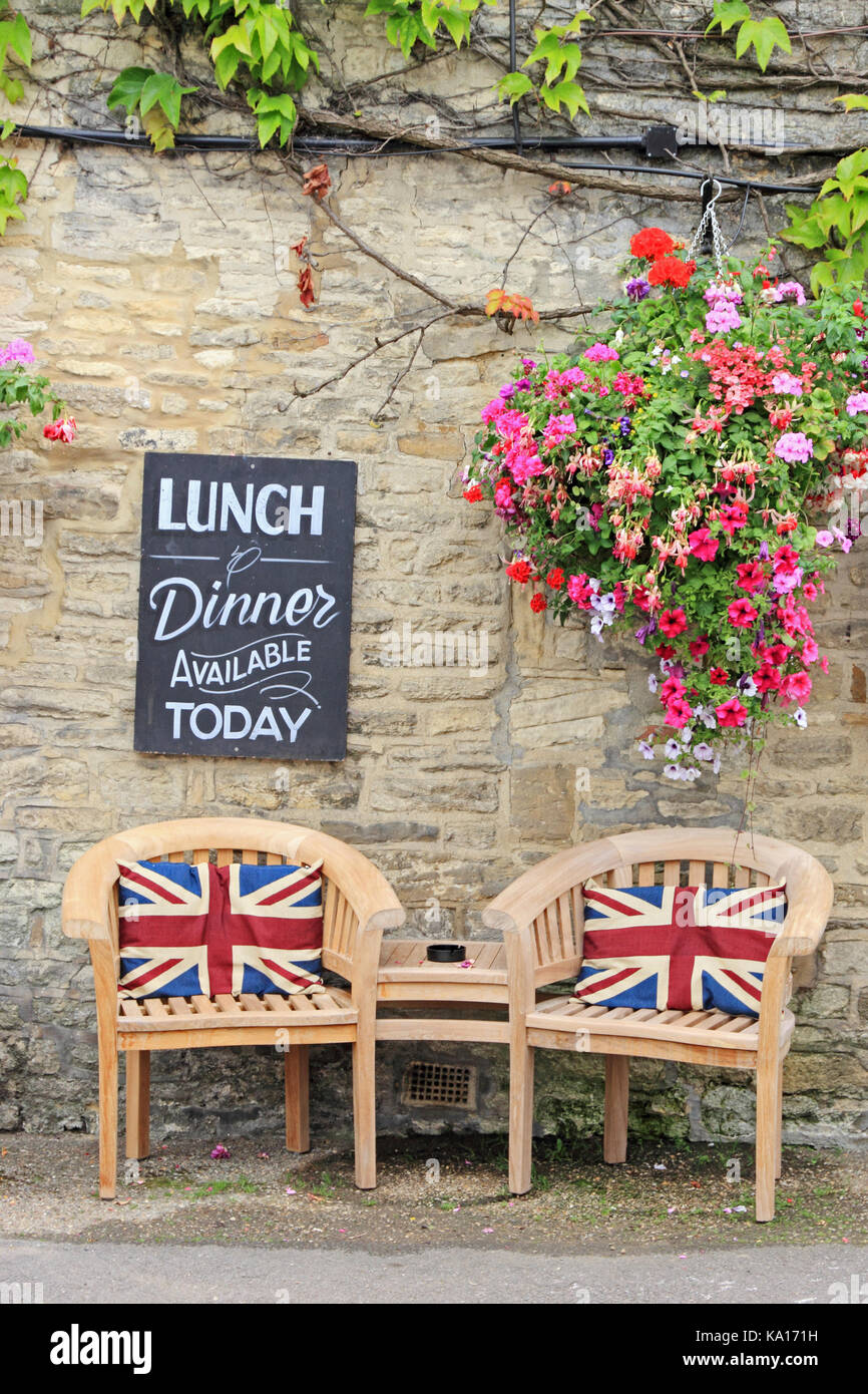 Hölzerne Stühle und Tisch mit Union Jack Kissen außerhalb Cotswolds Public House. Stockfoto