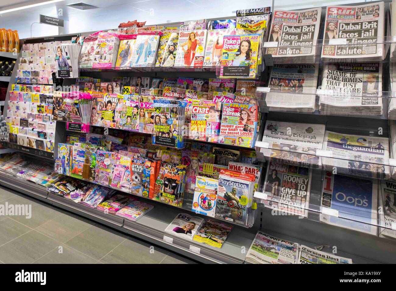 Zeitungen und Zeitschriften auf Anzeige auf einem Regal im Supermarkt Zeitungsstand speichern. Stockfoto