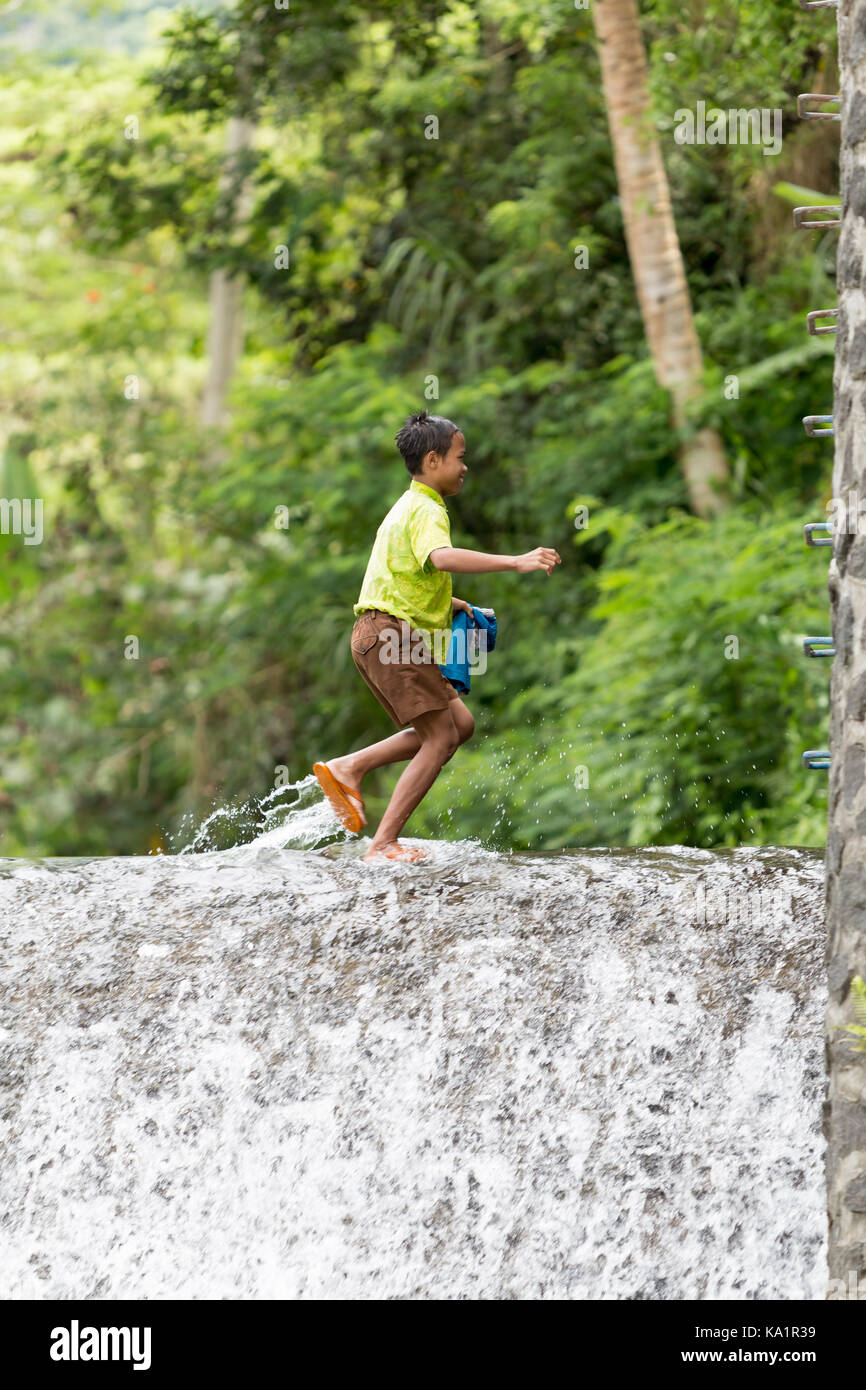 Kinder aus dem kleinen Dorf unter Mount Agung spielen in watterfall Stockfoto