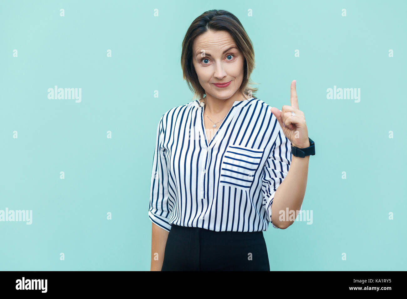 Schande über Sie! Cute business Arbeiterin Lady Finger nach oben zeigen und lächelndes Gesicht. Hellblauer Hintergrund Stockfoto