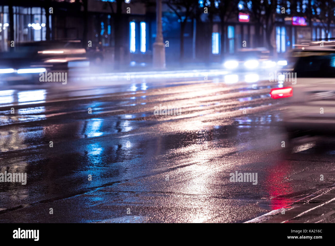Autos in Bewegung in der Nacht mit Scheinwerfer eingeschaltet. Verschwommene Sicht auf die City Road. Stockfoto
